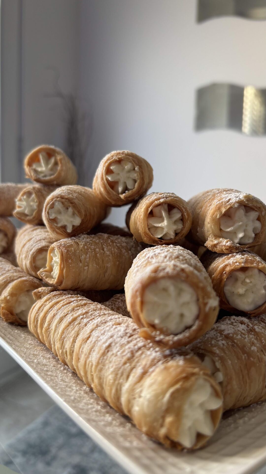 Twenty PastryVille cream rolls stacked on a tray